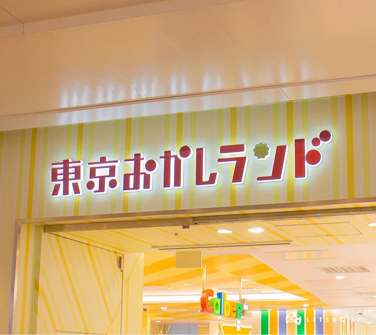「東京點心樂園(東京おかしランド)」入口招牌,背景可見黃白條紋牆面與室內燈光。